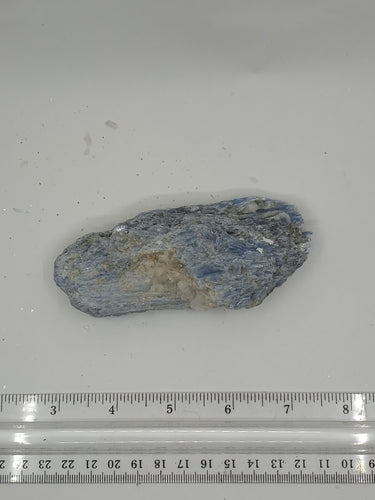 A rare kyanite stone with measurement scale on a serene white background.