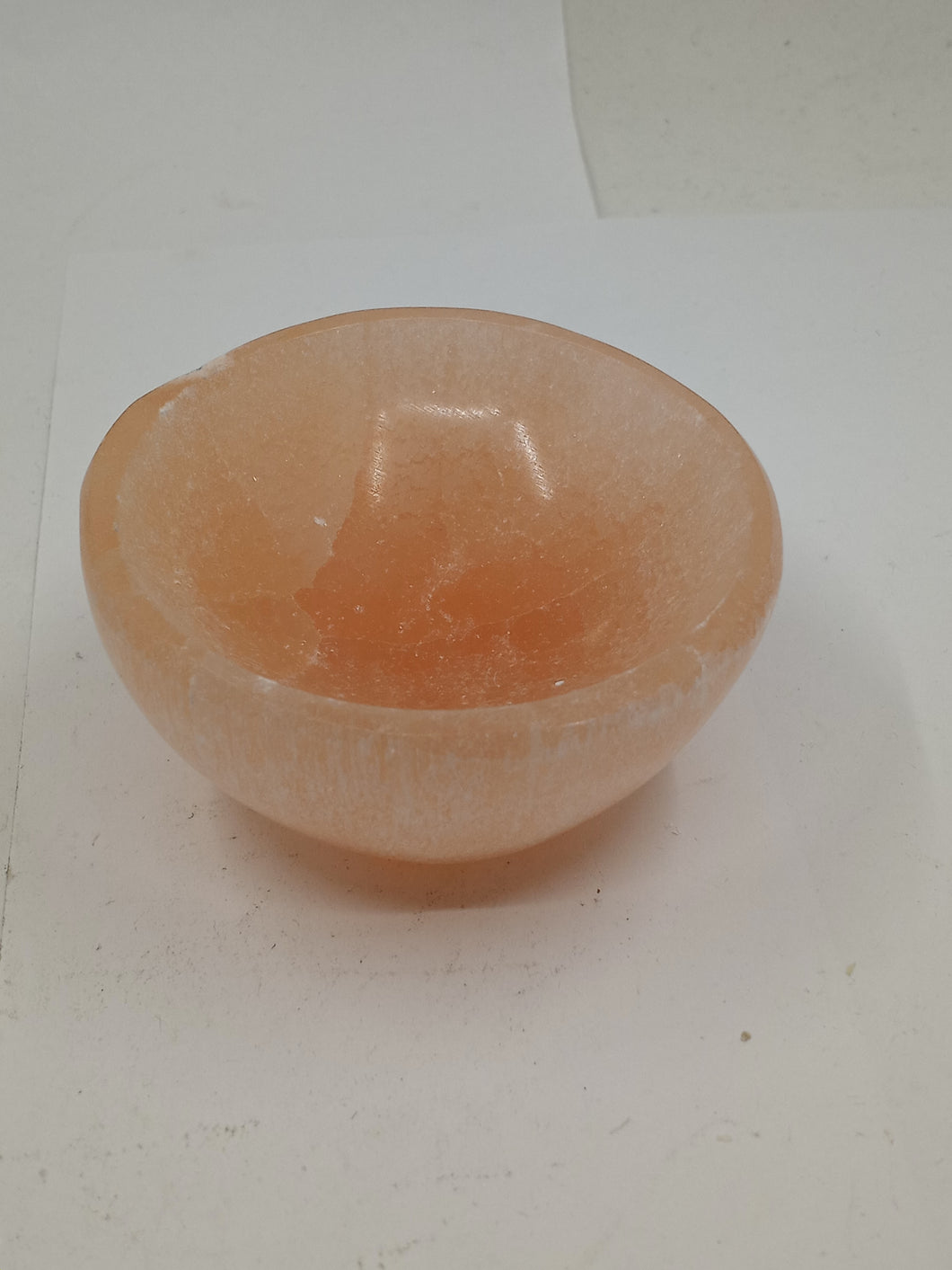 Orange selenite bowl on a white background.