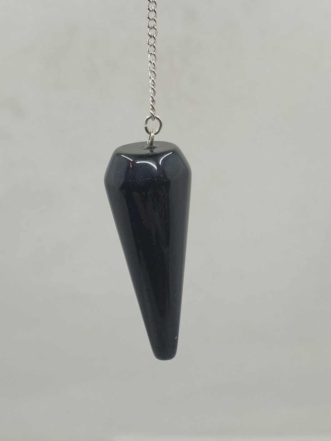 A beautiful shining black Obsidian Rounded Pendulum elegantly hangs from a silver chain.