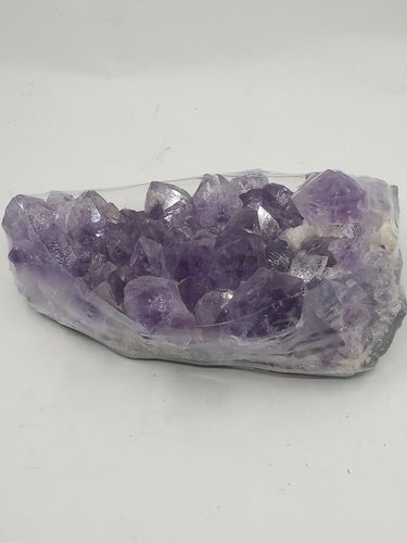 A amethyst cluster crystal with deep purple hues on a serene white background.