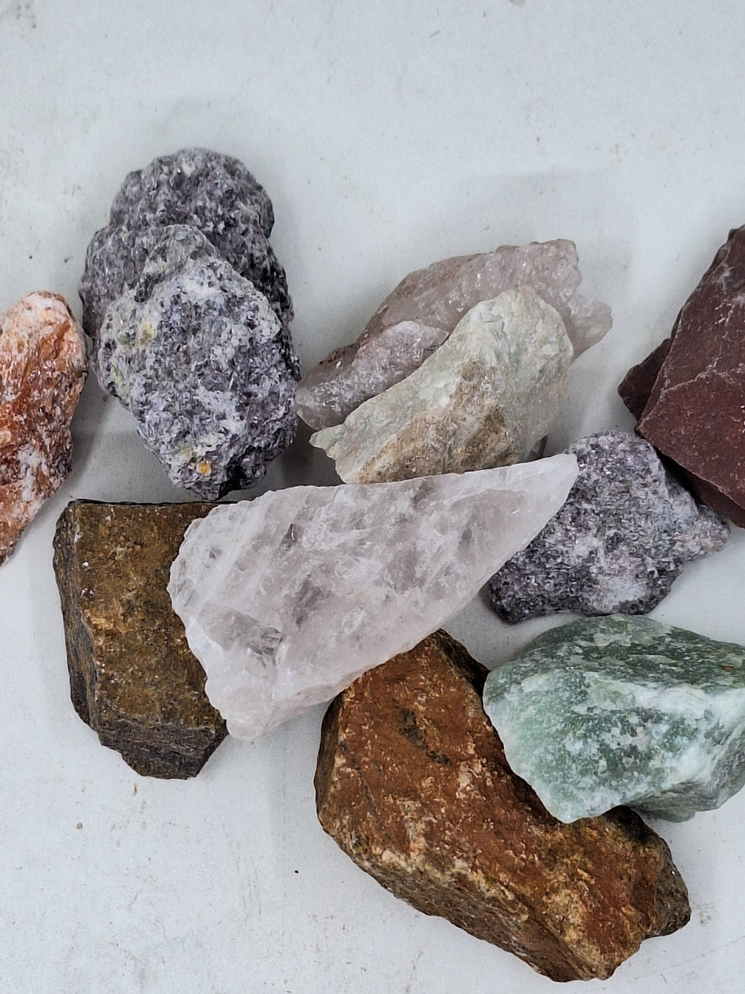 A collection of Brazilian mixed gemstone chips raw 250g healing stones on a serene white background.