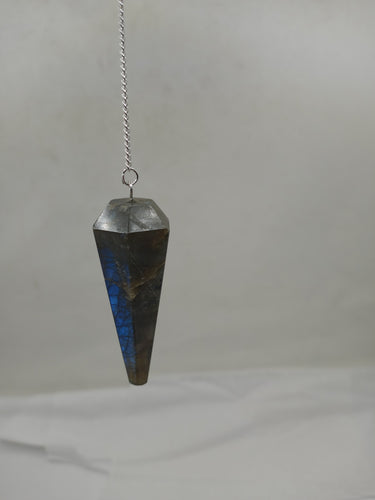 A labradorite faceted pendulum elegantly hangs from a silver chain on a serene white background.