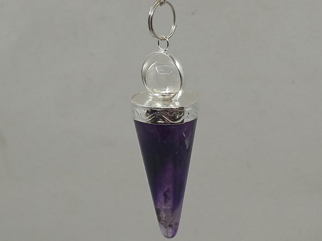 A stunning purple amethyst pendulum with a faceted point on a serene white surface.