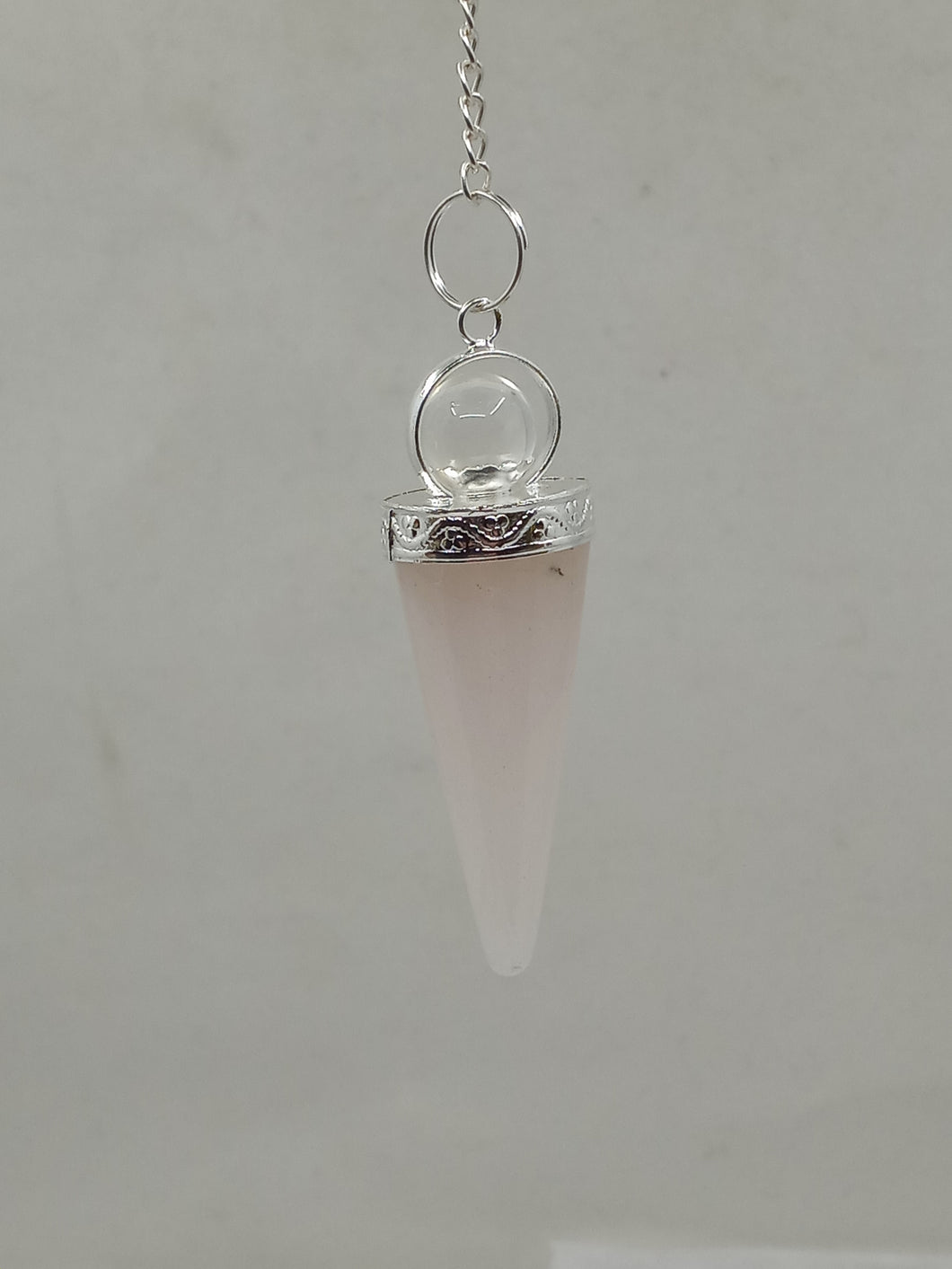 A Rose Quartz 2 pc Pendulum with a faceted point. The pendulum hangs from a silver chain.