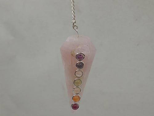 A chakra stones pendulum rose quartz with different 7-colour  hangs from a silver chain on a serene white background.