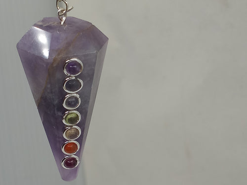 A beautiful 7-colour Chakra Stone Pendulum Amethyst with a faceted point on a serene white background.