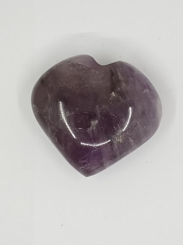 A purple heart-shaped Amethyst Puffy Heart Stone resting on a white surface.