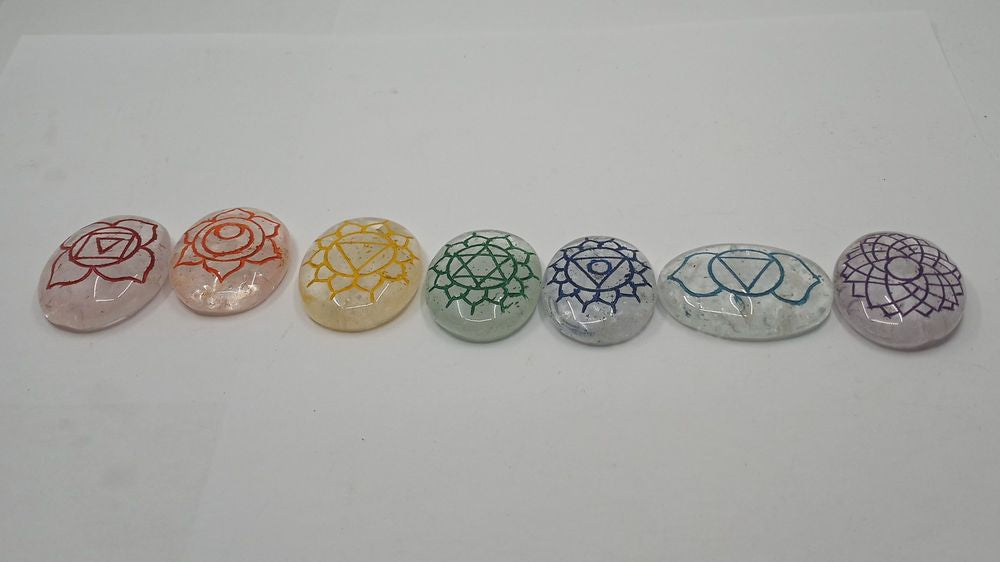 A set of seven colorful, oval-shaped chakra stones arranged in a row with a polished finish.