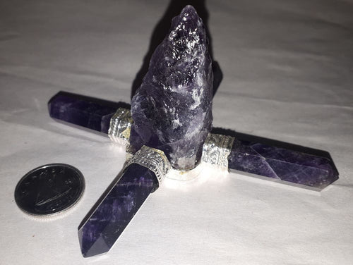 An amethyst aura energy generator with rough stone next to a coin on a serene white surface.