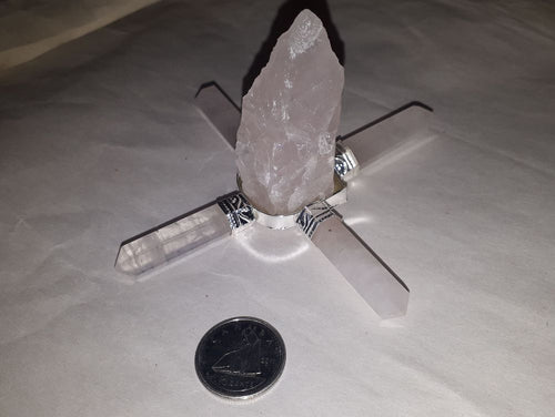A rose quartz aura energy generator rough clear stone with a coin on the serene white surface.