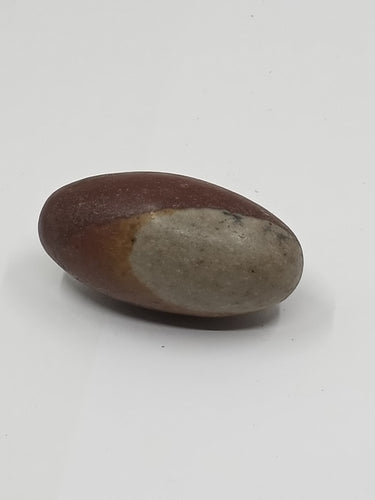 A Narmada shiva lingham egg stone with brown and gray hues on a white background.