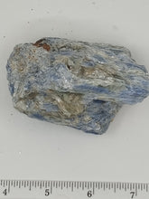 Load image into Gallery viewer, A kyanite stones in blue hues with streaks of gray and white, unique shapes with scale on a serene white surface.
