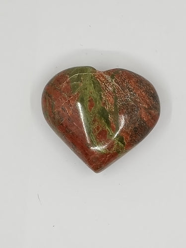 A heart-shaped unakite stone in red and green on a white background.