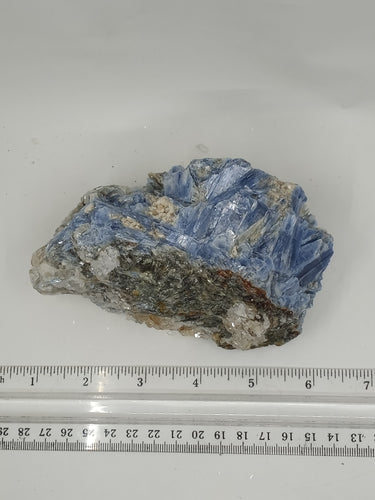 A rare kyanite stone with blue and black streaky on serene white surface.