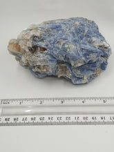 Load image into Gallery viewer, A rare kyanite stone with a streaky blue and white with a scale on serene white surface.
