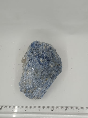 A blue and white streaky kyanite stone on serene white surface, unique and beautiful.