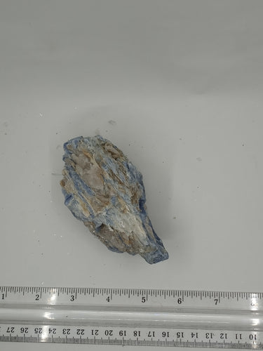 A kyanite stones with a streaky blue gray and white with scale a serene white surface.